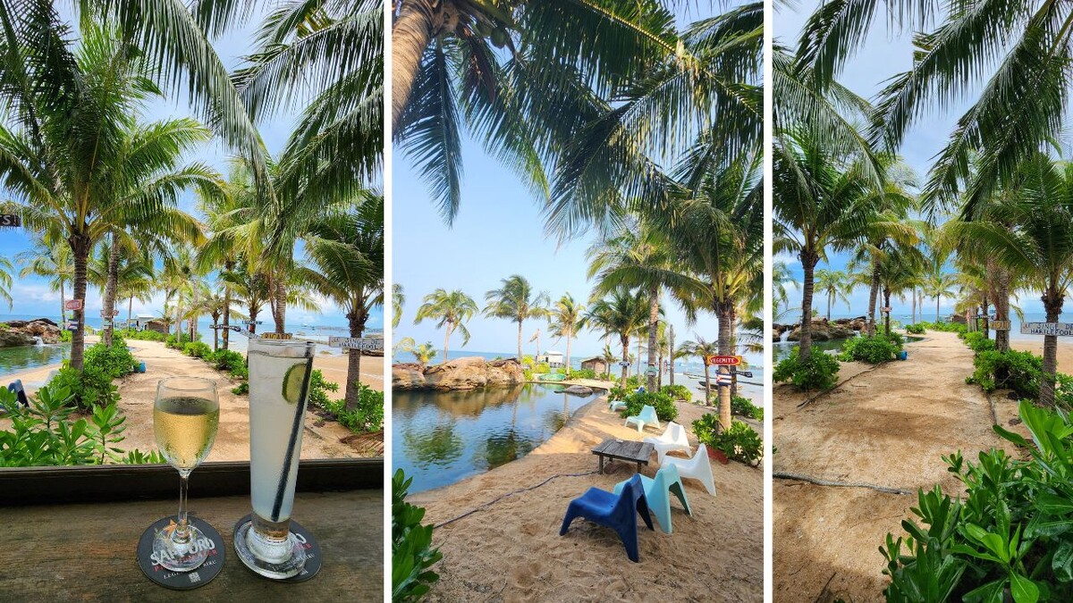 Wine and a gin and tonic on a bar table, and colorful chairs beside the rock pool under palm trees at Rory's Beach Bar, Phu Quoc