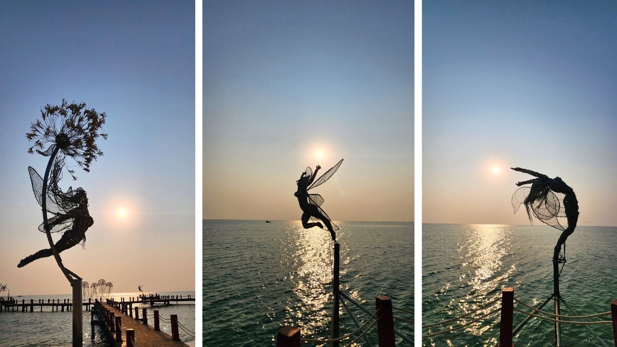 Silhouetted wire sculptures of flying human figures frozen mid-leap against the sunset sky at Sanato Beach, Phu Quoc