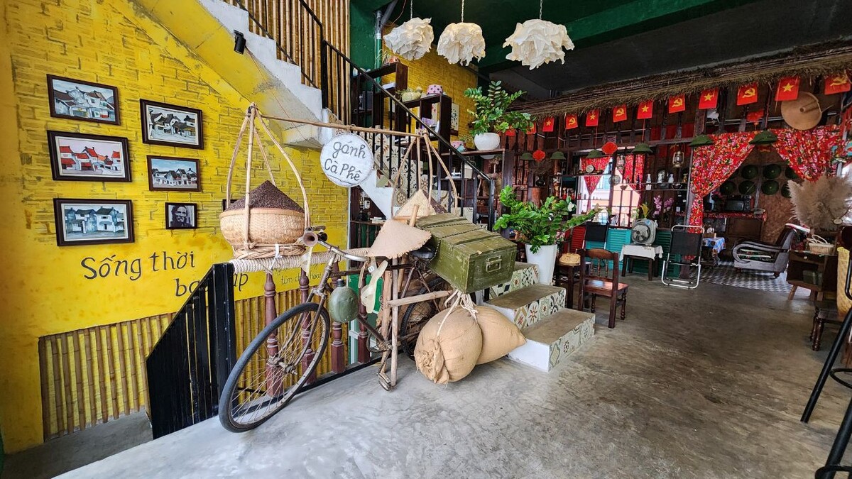 Retro-themed interior of Tiem Ca Phe Thoi Bao Cap cafe in Sunset Town, Phu Quoc, decorated with a vintage bicycle and old propaganda-era artifacts