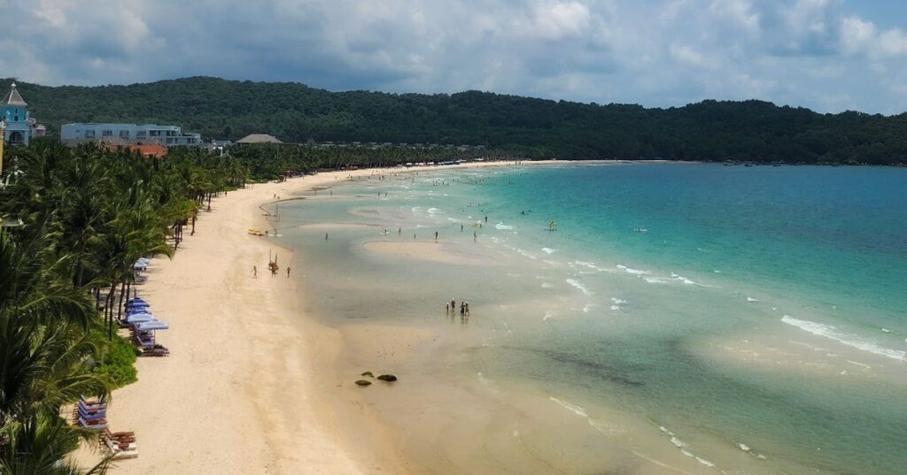 Phu Quoc travel guide: aerial view of a wide bay beach with swimmers and resort buildings on Phu Quoc