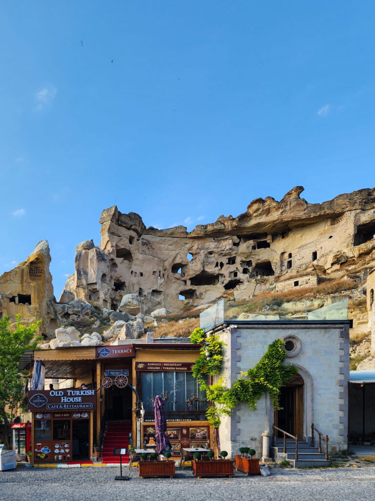 Old Çavuşin cave village above cafés and stone buildings in Cappadocia