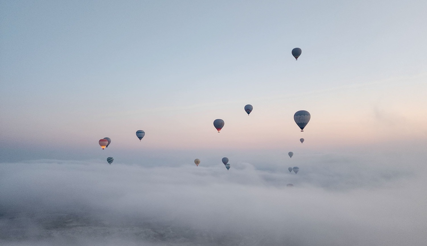 Hot air balloons floating above clouds at sunrise in Cappadocia