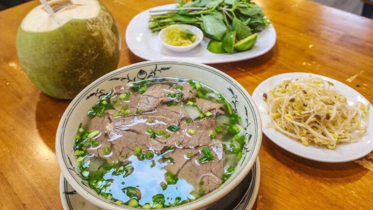 Beef pho in Vietnam with fresh herbs, bean sprouts, lime and a coconut