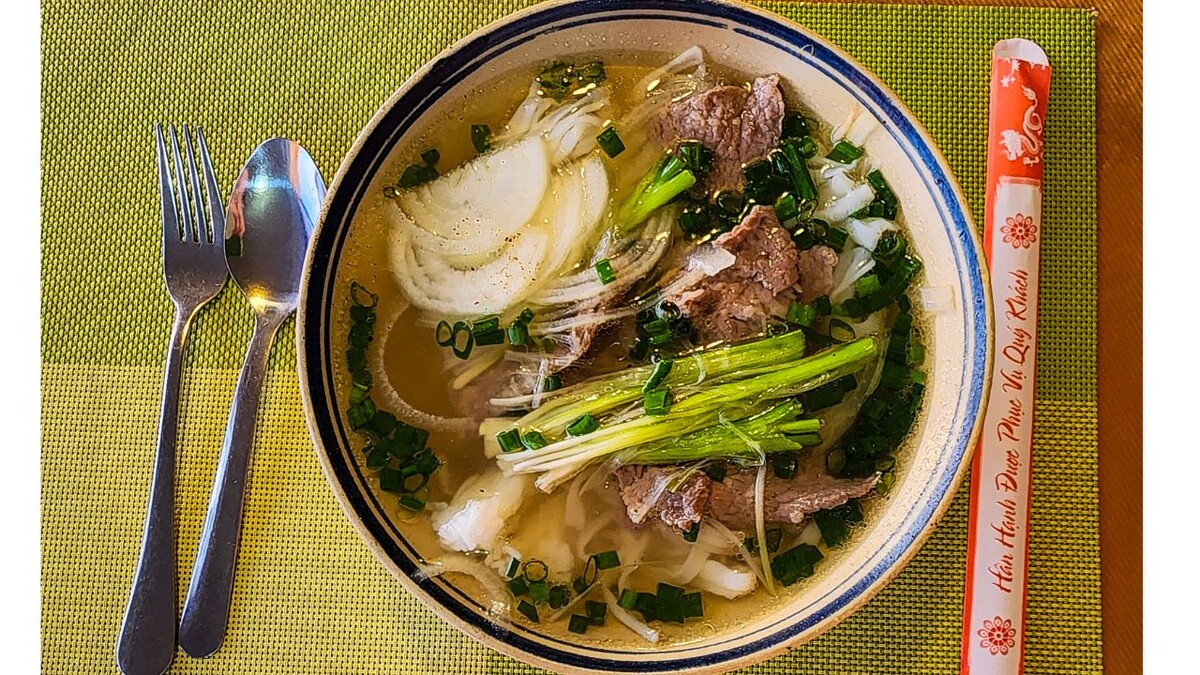 Beef pho with sliced onion, spring onions and rice noodles