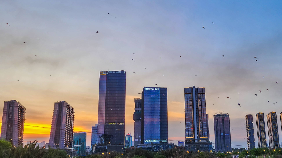 Sunset behind modern towers in Ho Chi Minh City with kites overhead